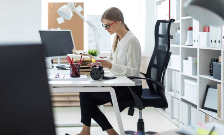 junge Frau sitzt an einem Schreibtisch und arbeitet.